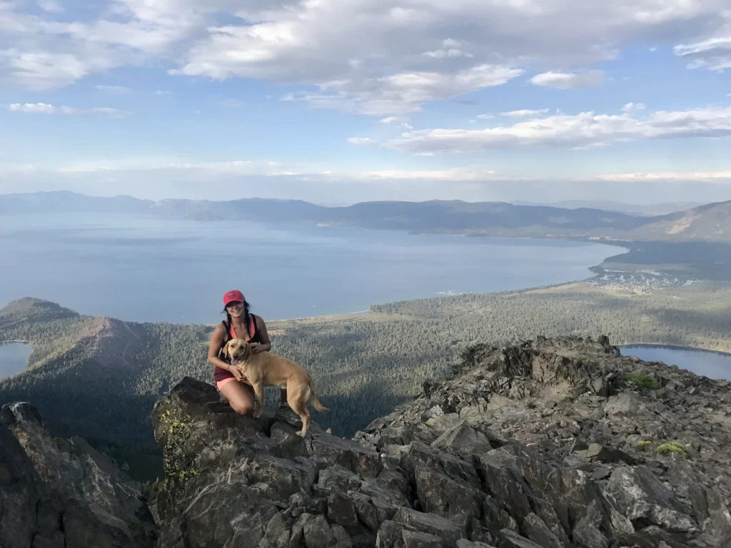 Kali sitting beside a dog on a scenic hiking trail